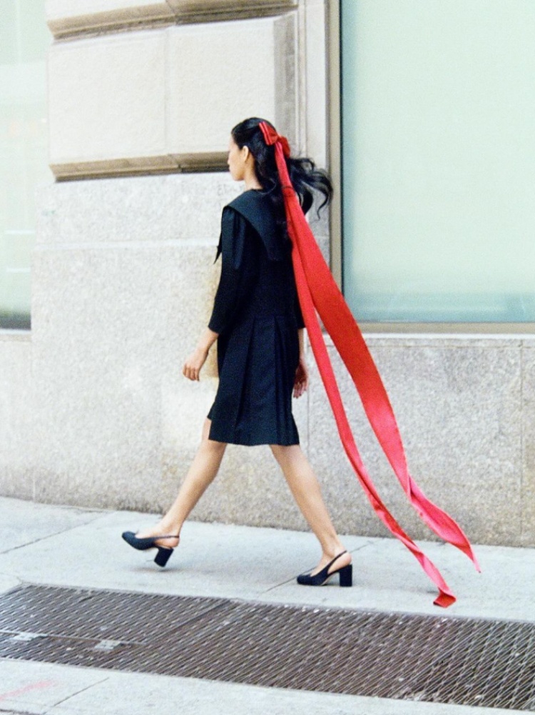 A model wearing a red bow in her hair