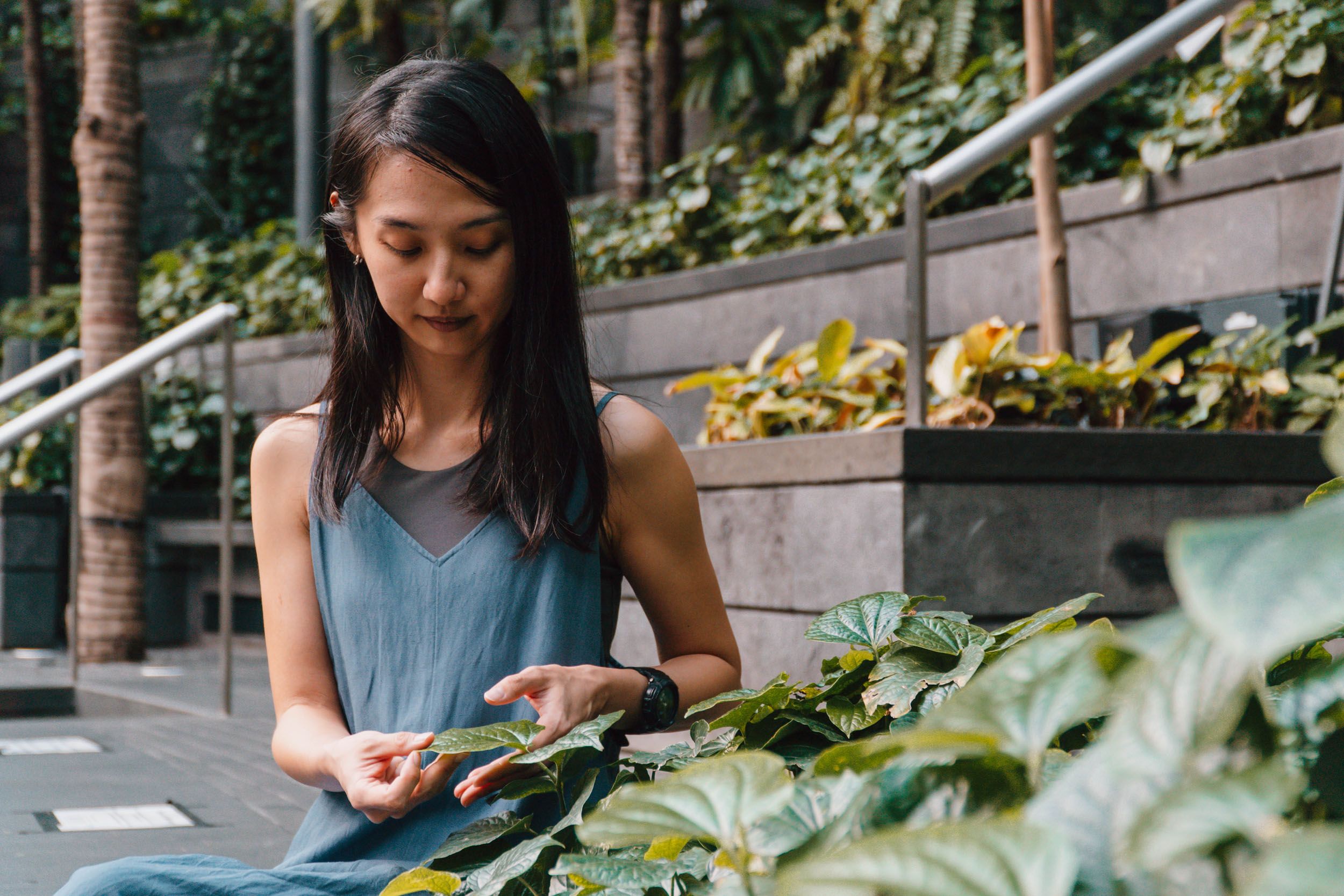 A woman examining a leaf in a garden